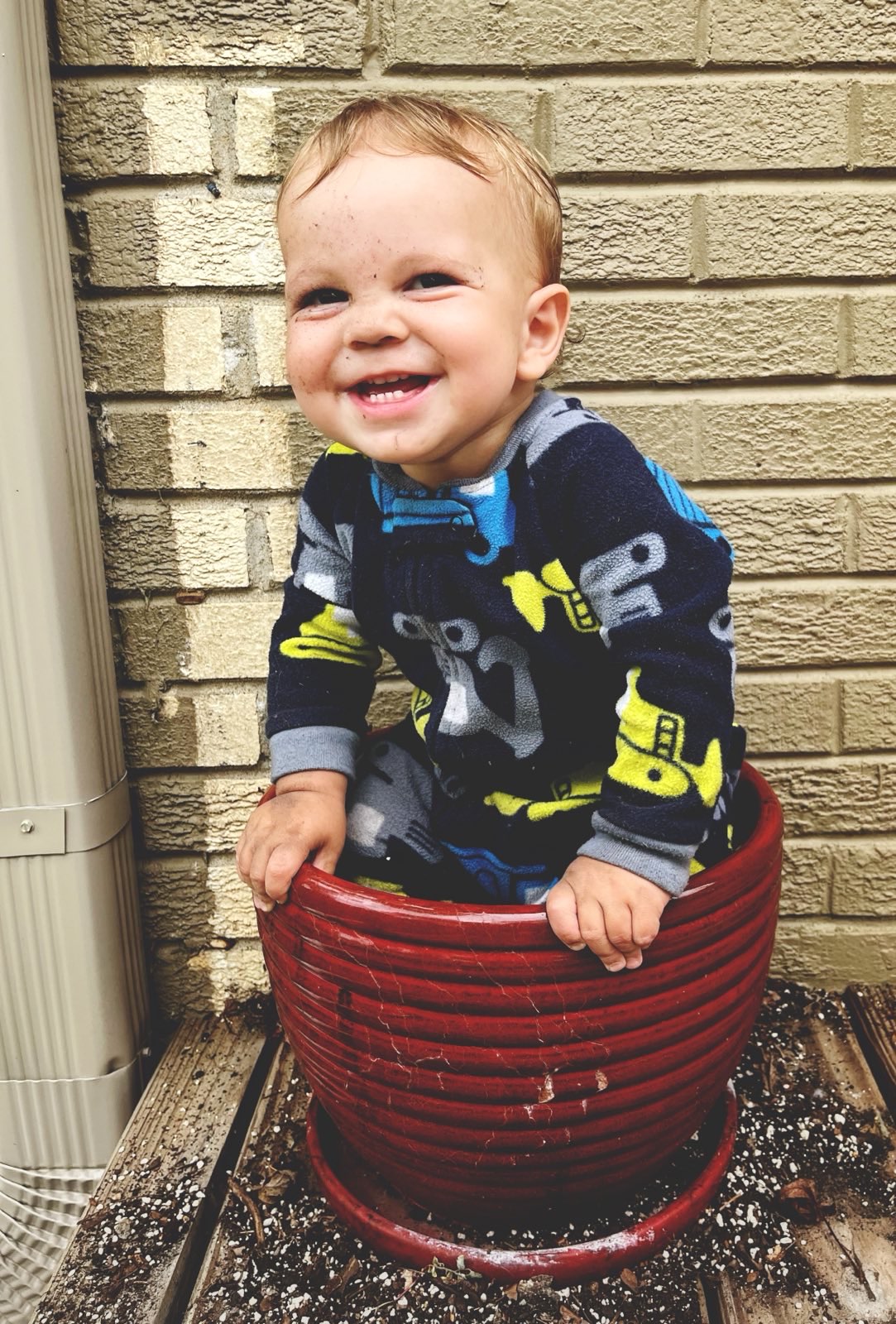 My baby playing in a large pot full of dirt